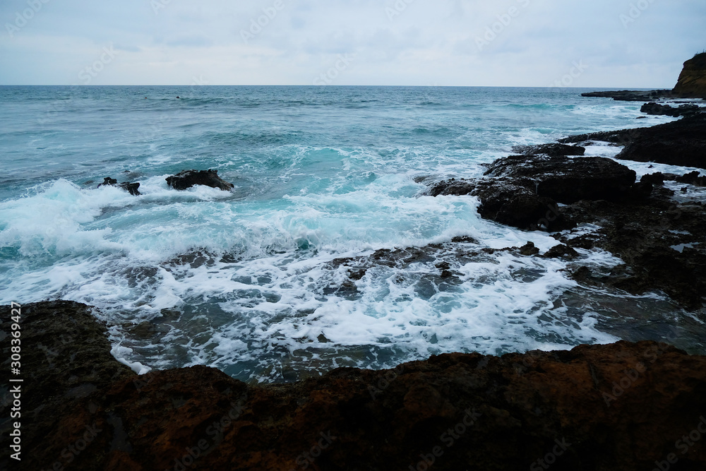 Waves on the seaside are splashing on the rocks in a stormy day