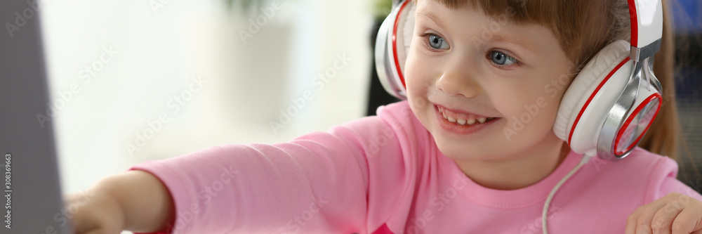 Little girl wearing headphones use mobile computer Little girl wearing headphones use mobile computer