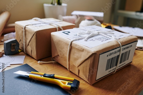 Wrapped and strapped packages ready to be delivered and boxcutter tool on table photo