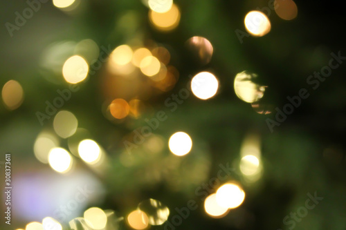 Christmas abstract blurred background with bokeh colorful circles. Artificial fir tree with led light garland. Festive holiday background.