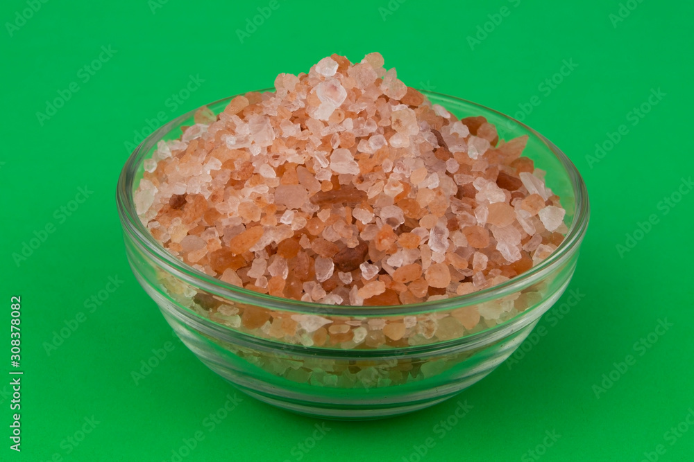 Himalayan pink rock salt in bowl on green background Himalayan pink rock salt in bowl on green background