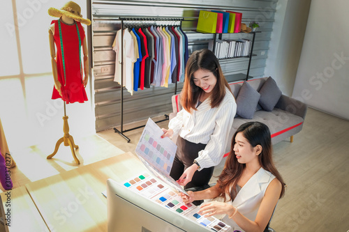 The designer is designing by comparing the color chart with the thread for designing clothes.