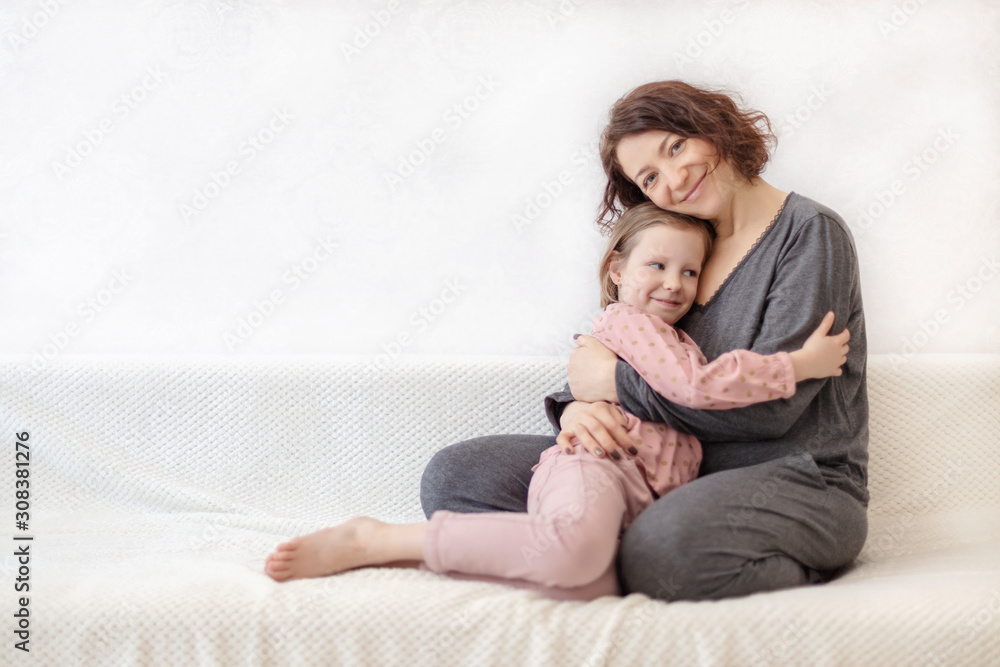 Young woman with her daughter are resting on the sofa.