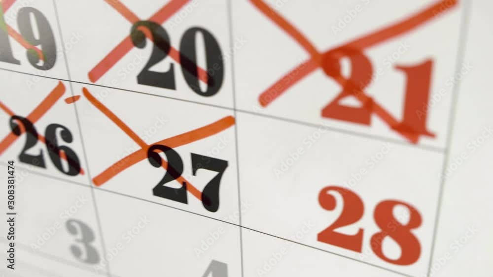 Female hand crosses with red marker the calendar day 27. Slow motion shot. Close up Female hand crosses with red marker the calendar day 27. Slow motion shot. Close up