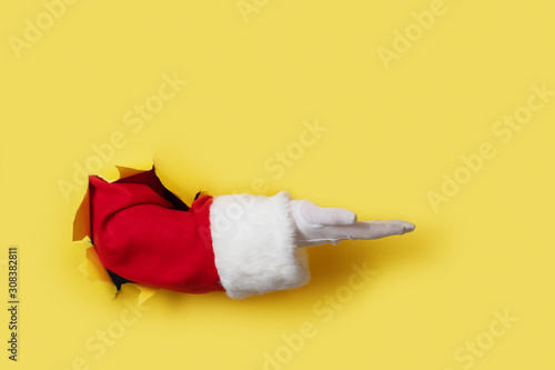 Santa Claus hand presenting your christmas text or product over yellow background photo