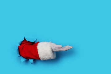Santa Claus hand presenting your christmas text or product over light blue background