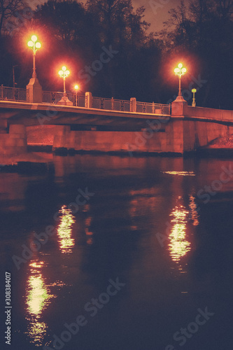 Night bridge with lanterns and their reflection above the neva river