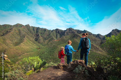 mother with kids hiking in mountains, family travel in nature
