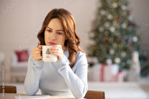 Fotografija Pretty yuoung woman with cup in her hands looking sad