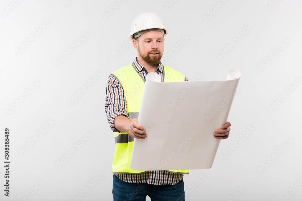 Successful engineer or foreman in helmet and workwear holding blueprint