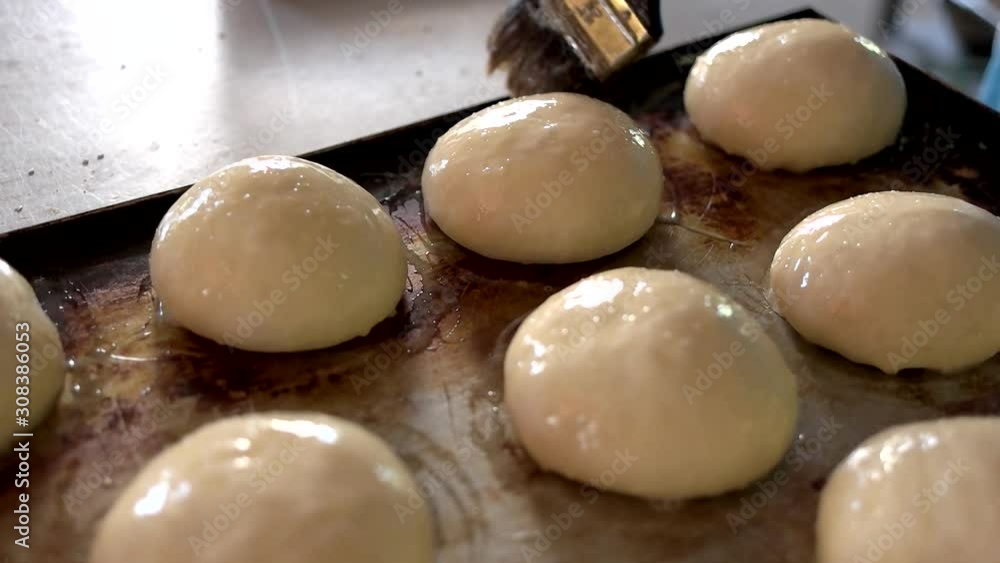 Baker hands smears yolks on buns dough. Preparation of bakery snacks. Homemade fresh bakery. Baker hands smears yolks on buns dough. Preparation of bakery snacks. Homemade fresh bakery.