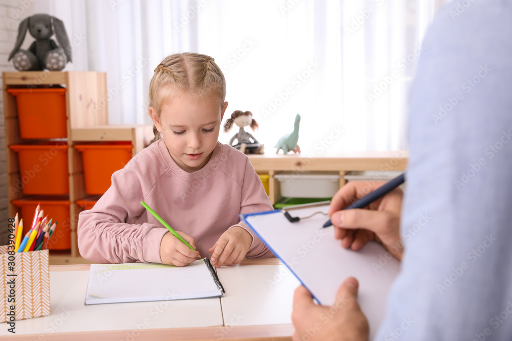 Little girl on appointment with child psychotherapist indoors Little girl on appointment with child psychotherapist indoors