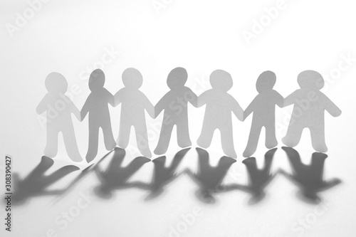 Paper people holding hands on white background. Unity concept