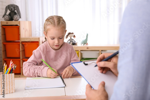 Little girl on appointment with child psychotherapist indoors