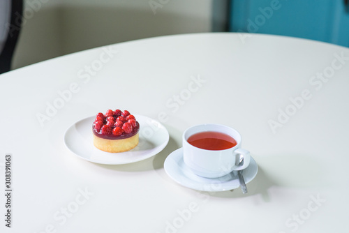 Delicious berry tea and tarte with raspberries on a table in a cozy coffee shop