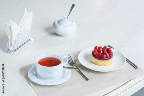 Delicious berry tea and tarte with raspberries prepared on a table for a guest in a cozy cafe