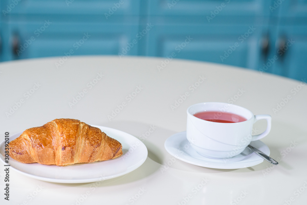 Fruit tea and delicious fresh croissant on the table in a cozy coffee shop Fruit tea and delicious fresh croissant on the table in a cozy coffee shop
