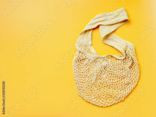 Zero waste, sustainable lifestyle, plastic free concept. Eco friendly natural mesh bag on yellow background. Empty net bag with copy space for text or design. Top view or flat lay