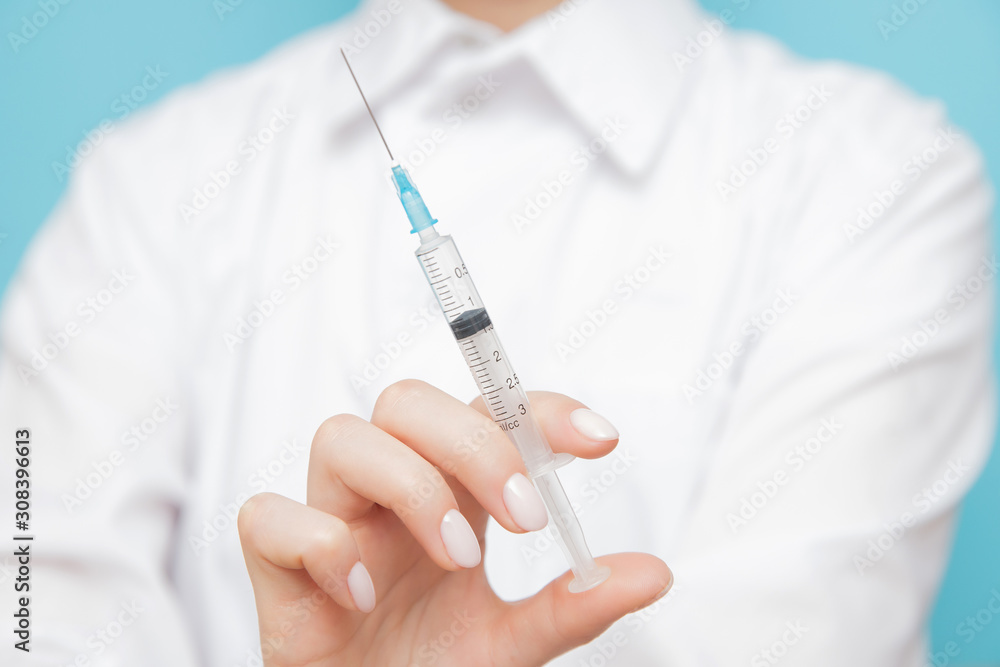 Beauty spa doctor holding syringe on blue background. Concept lip enlargement injection, anti-aging serum, plastic surgery Beauty spa doctor holding syringe on blue background. Concept lip enlargement injection, anti-aging serum, plastic surgery