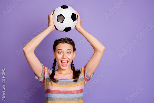 Portrait of excited funky teenager girl hold soccer ball support her team play world cup match win victory scream wow omg wear youth modern clothes isolated over violet color background photo