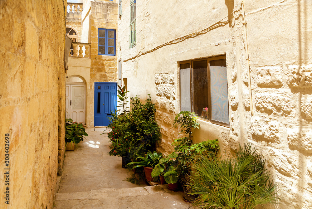 An empty narrow street with traditional Maltese architecture