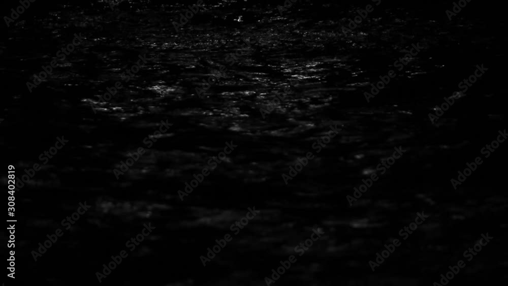 The defocused view of river stream water slowly flowing through natural rock beach at night. Abstract nature background.