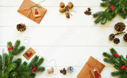 Christmas frame made of fir branches, red berries, spices, nuts and gifts on rustic wooden table. Christmas holiday background. Flat lay, top view, copy space.