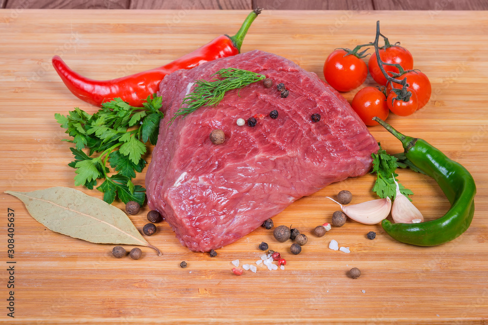 Piece of uncooked beef among vegetables, greens and spices Piece of uncooked beef among vegetables, greens and spices