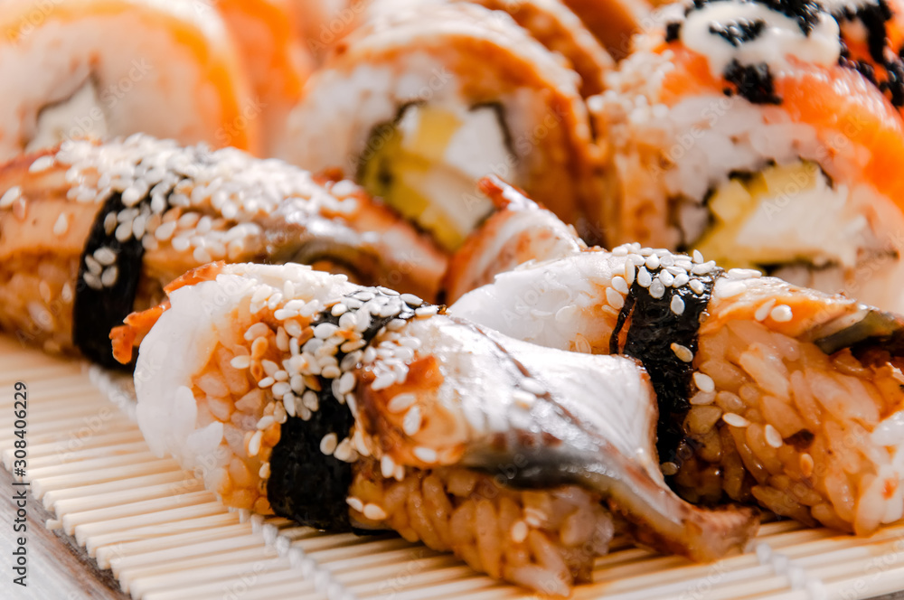 Sushi and soy sauce in a bowl and wooden chopsticks on a gray wooden table. Japanese food. Sushi Set. Variety of rolls. Menu. Sushi and soy sauce in a bowl and wooden chopsticks on a gray wooden table. Japanese food. Sushi Set. Variety of rolls. Menu.