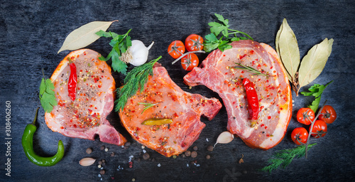 Pickled uncooked pork loin slices, spices, greens on black surface