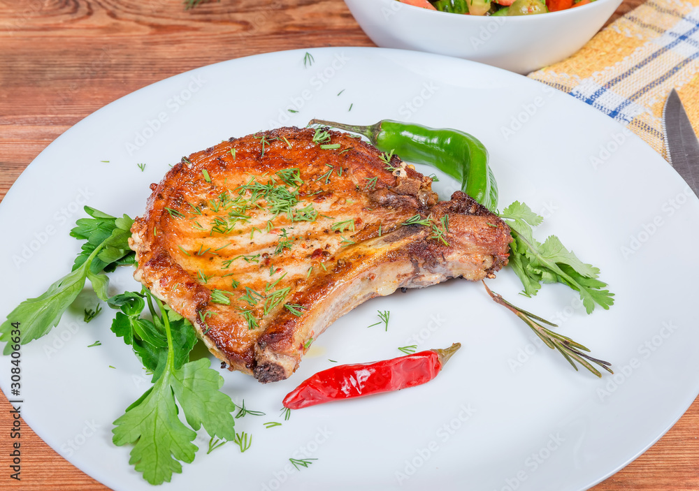 Grilled pork loin chop bone-in on dish close-up Grilled pork loin chop bone-in on dish close-up