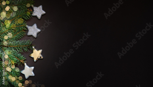 Christmas modern composition. Fresh fir tree branches, shiny silver stars on dark background. Christmas, New Year, winter concept. Flat lay, top view, copy space.
