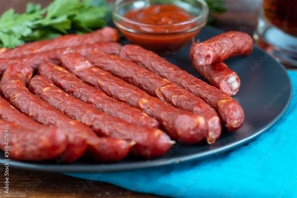 Smoked sausages on a dark plate. Nearby a large glass of dark beer. Copy space.