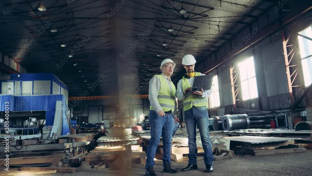 Professional heavy Industry Engineers. Two workers are talking in a building materials factory Professional heavy Industry Engineers. Two workers are talking in a building materials factory