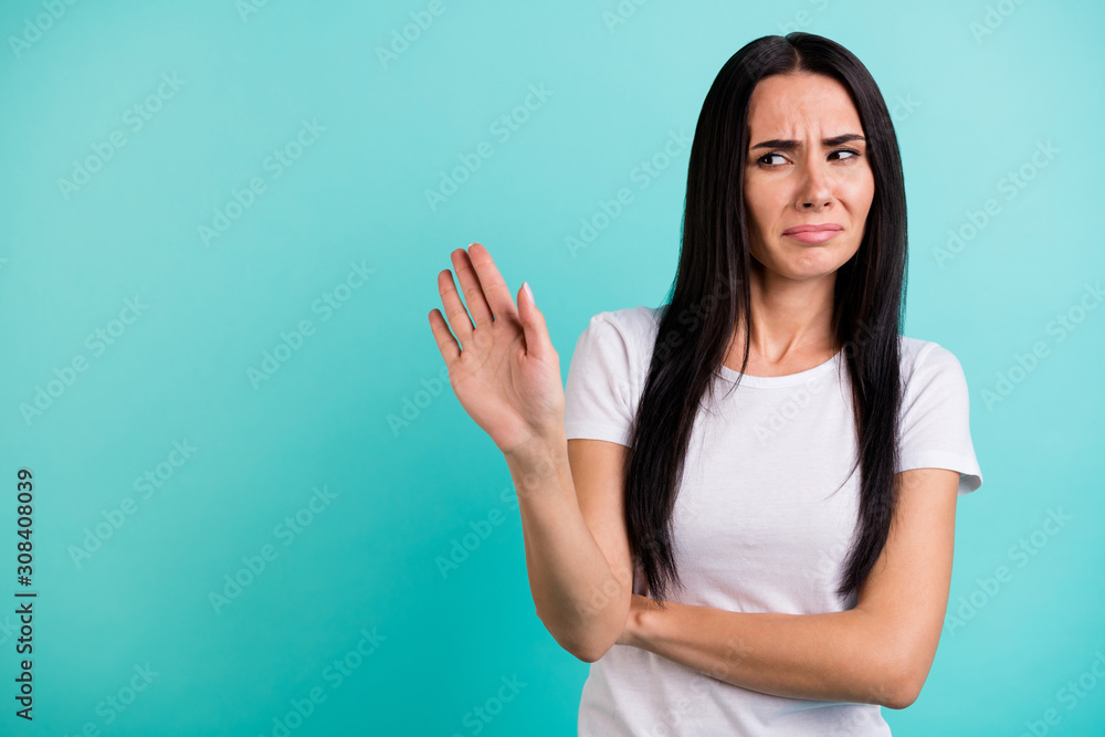 Fototapeta premium Photo of discontented casual woman gesturing with her palm to stop moving towards her grimacing in being disgusted isolated vivid teal color background