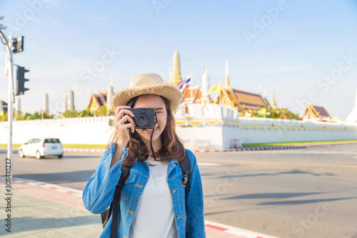 Canvas Print Traveler Asian woman in jeans jaket wearing a backpack take a picture by her cam