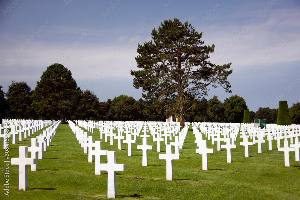 COLLEVILLE-SUR-MER, FRANCE. JULY 25, 2018: II World War soldiers graves among trees at the Memorial of American cemetery in Collevile, Normandy. In Omaha beach. COLLEVILLE-SUR-MER, FRANCE. JULY 25, 2018: II World War soldiers graves among trees at the Memorial of American cemetery in Collevile, Normandy. In Omaha beach.