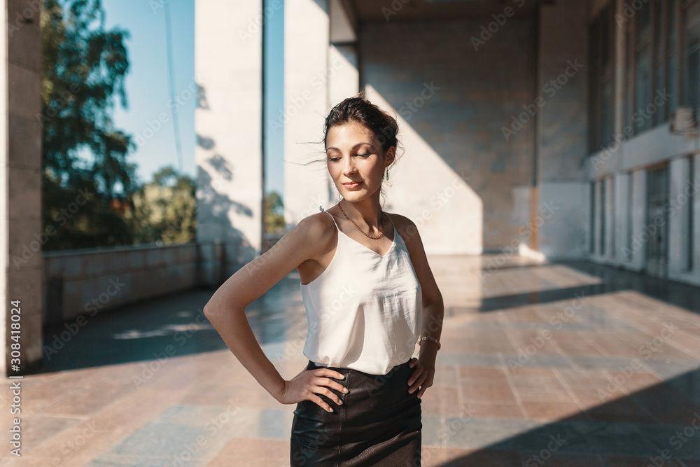 Smiling pretty woman holding hands on the hips while posing in the city Smiling pretty woman holding hands on the hips while posing in the city