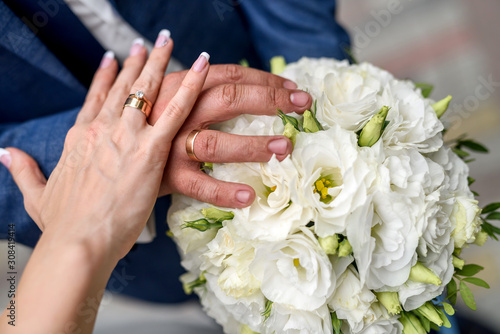 Wedding concept. Male and female hand with golden rings on flower bouquet
