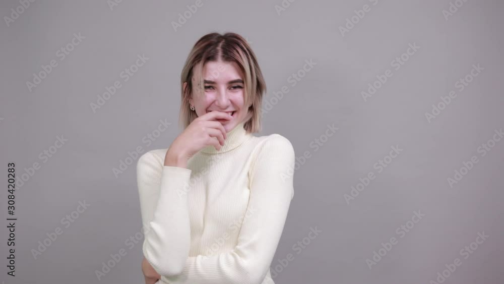 Boring young caucasian woman posing isolated on gray background in studio wearing casual shirt, keeping hand on chin Boring young caucasian woman posing isolated on gray background in studio wearing casual shirt, keeping hand on chin