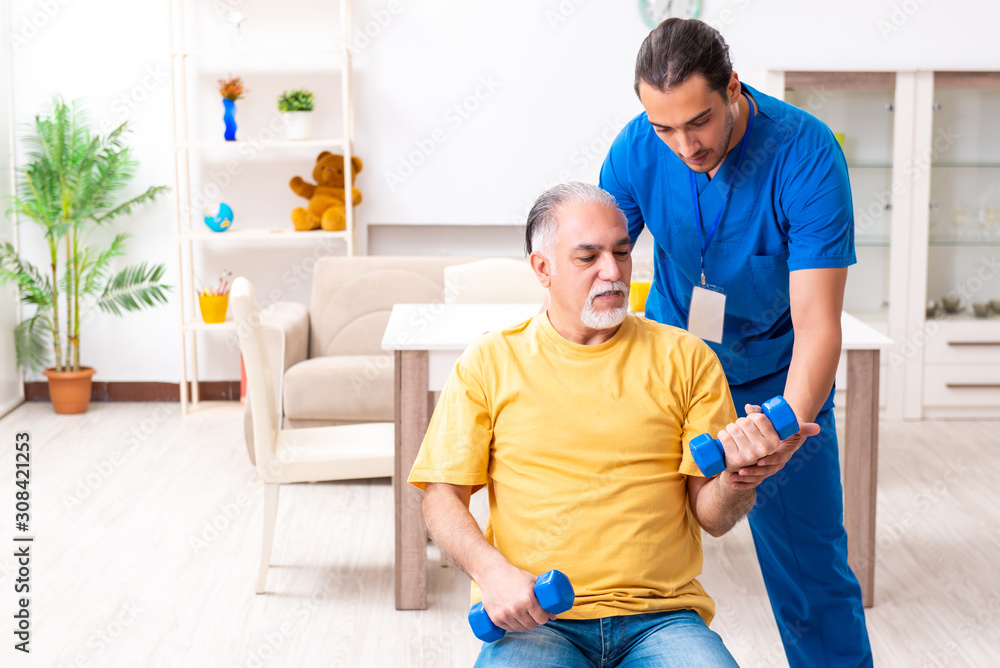 Obraz premium Young male doctor visiting old patient at home