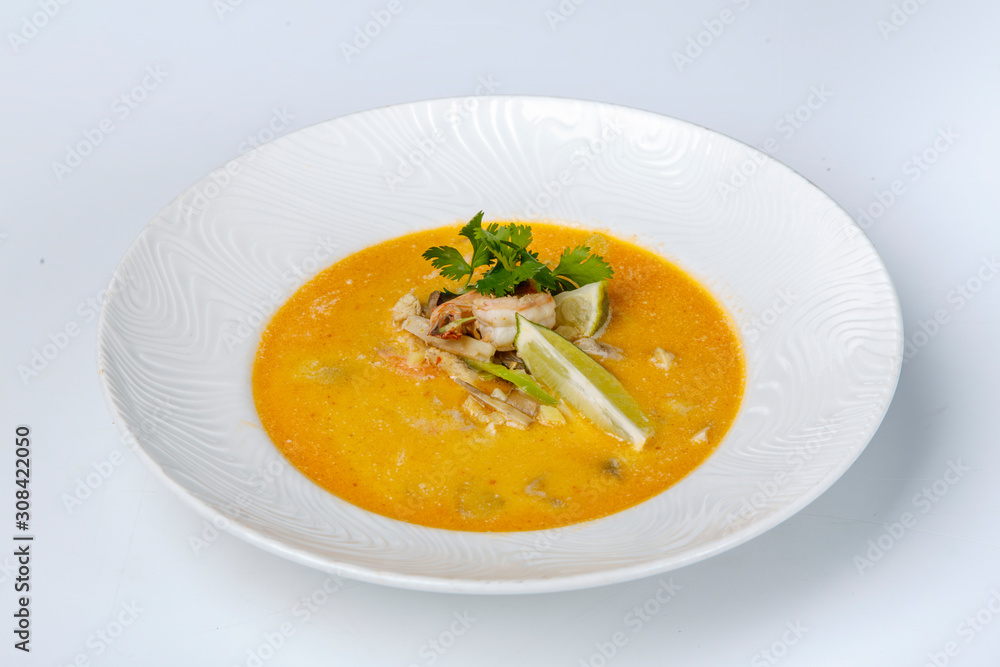 Cheese soup with shrimp. Yellow soup is decorated with lemon and parsley. On white background Cheese soup with shrimp. Yellow soup is decorated with lemon and parsley. On white background