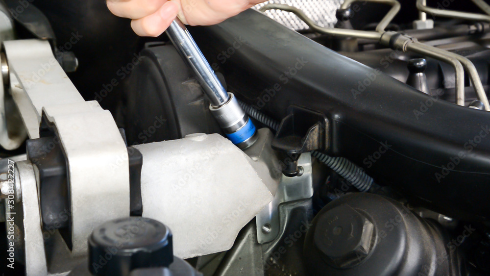 Mechanic uses socket wrench tighten nut of diesel engine.