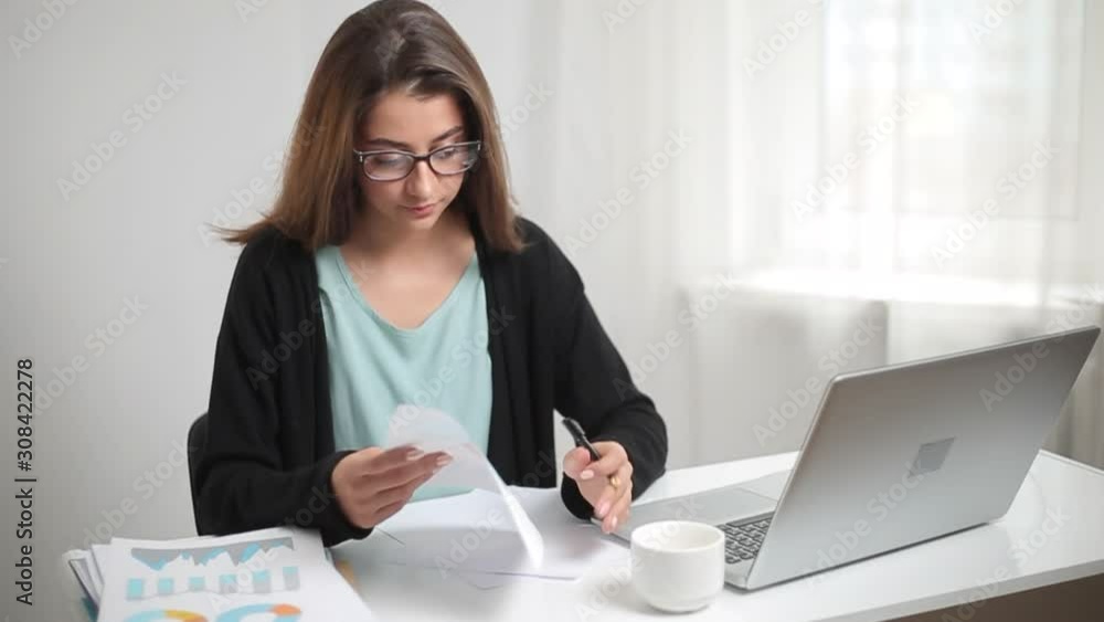 Indian business woman working on laptop with financial charts in a modern office. Indian business woman working on laptop with financial charts in a modern office.