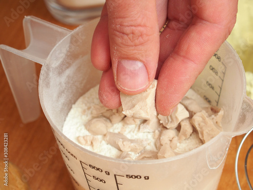 Adding fresh yeast into measuring cup. Making yeast pancakes (crepes). photo