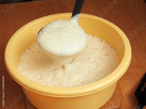 Using ladle pour batter into frying pan. Making yeast pancakes (crepes). photo