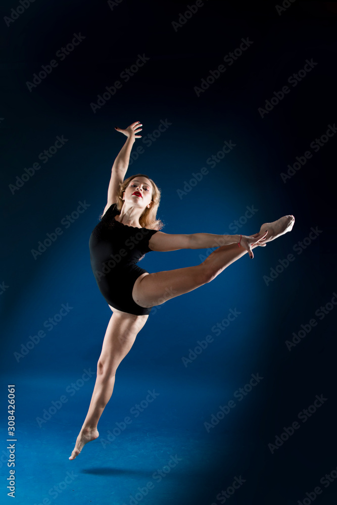 girl dancer in a jump and a beautiful pose on a blue background