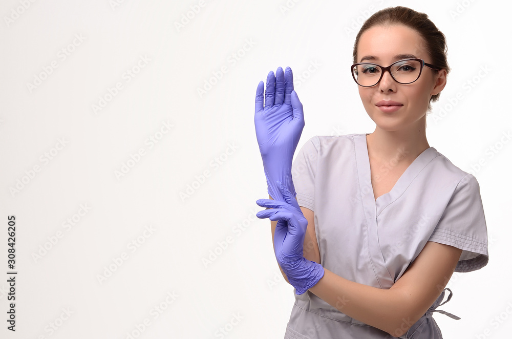 Beautiful female doctor, medical assistant or nurse wearing glasses, putting on latex or rubber gloves on white background. Health care concept. Copy space for your text Beautiful female doctor, medical assistant or nurse wearing glasses, putting on latex or rubber gloves on white background. Health care concept. Copy space for your text