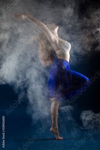 Fototapeta Naklejka Na Ścianę i Meble -  girl dancer in a jump and a beautiful pose on a blue background