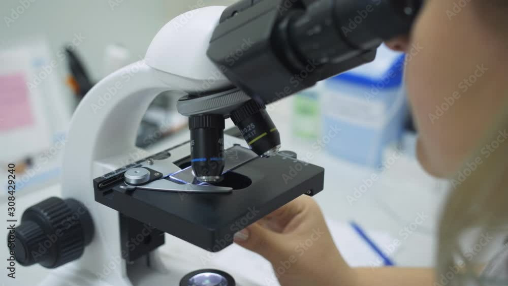 Woman biologist working with microscope in laboratory, close-up. Woman biologist working with microscope in laboratory, close-up.